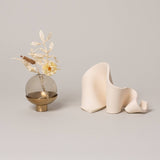 Furl Art Object, Bone displayed beside flowers