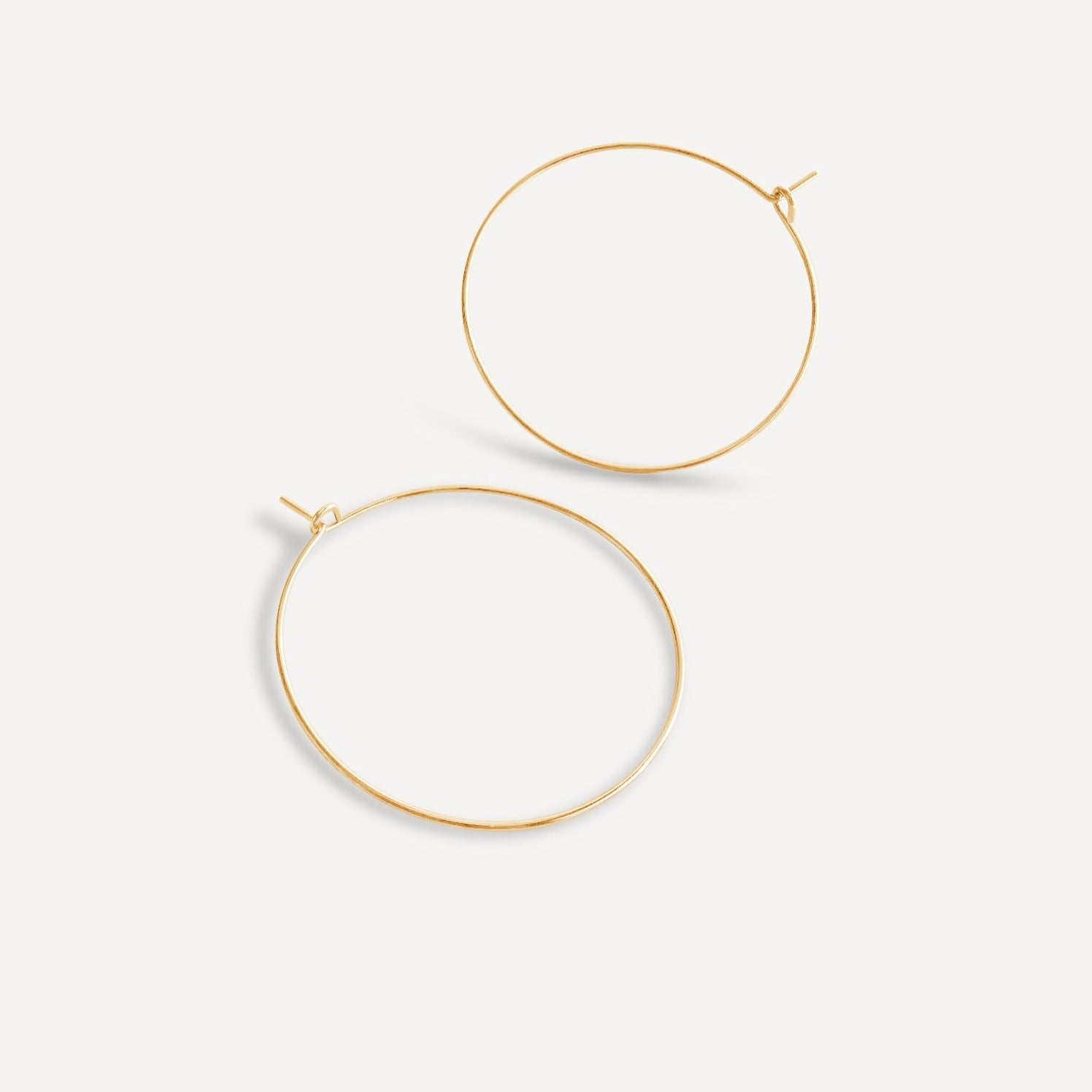 Pair of 1.5-inch gold fill essential hoop earrings on a white background.