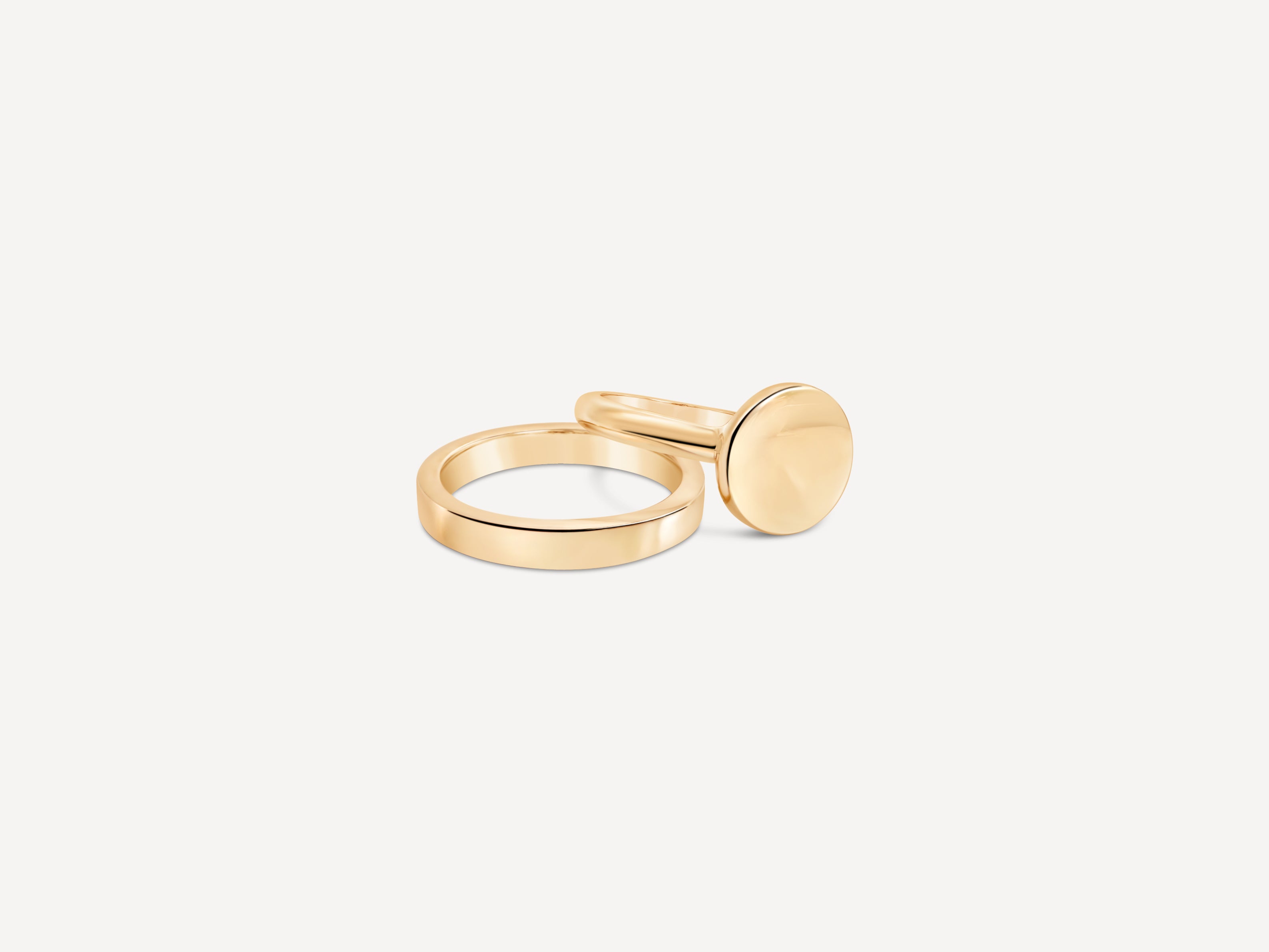 A stack of gold rings, including the signet ring, arranged on a neutral background to showcase variety.