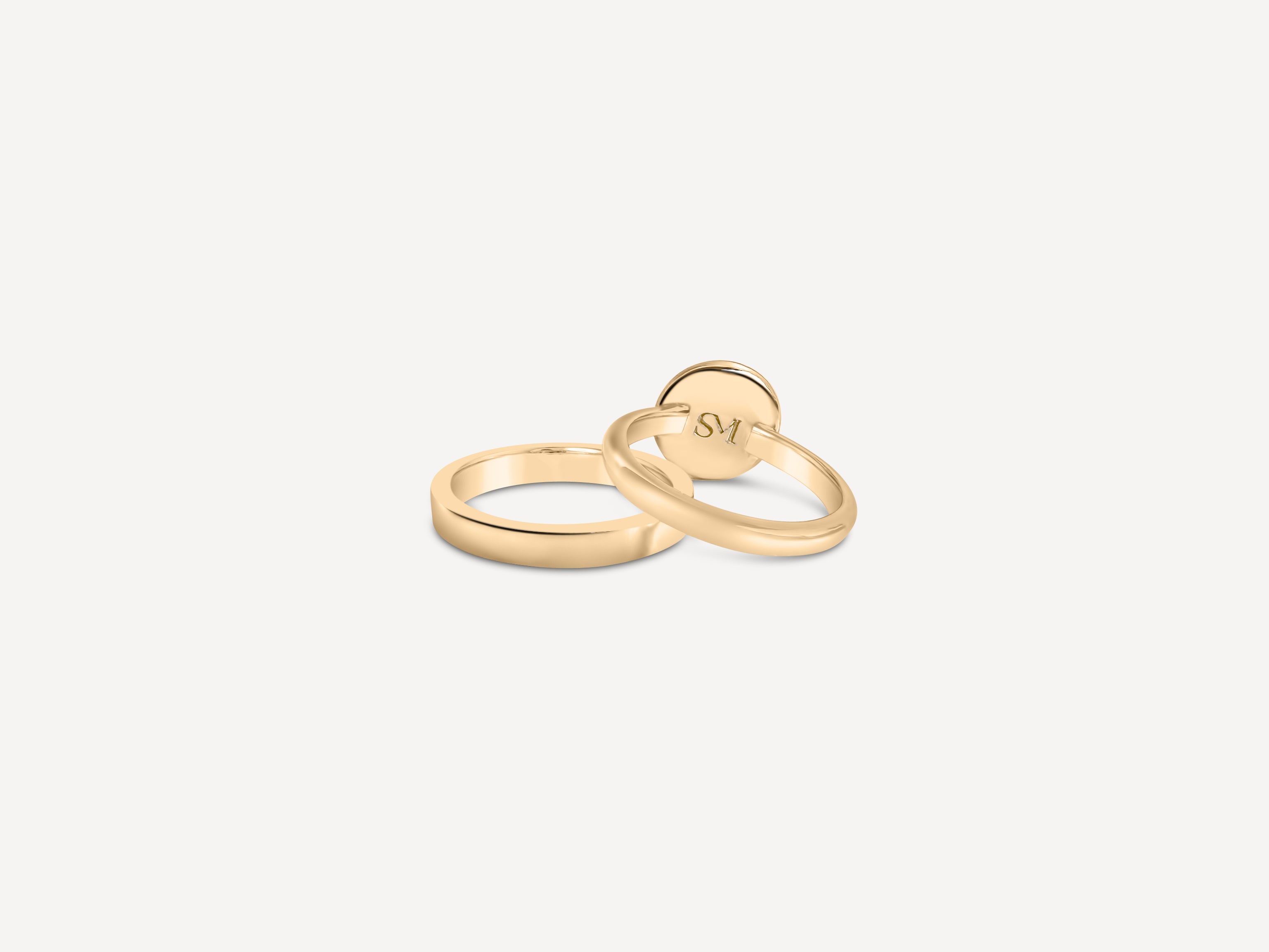 A stack of gold rings, including the signet ring, arranged on a neutral background to showcase variety.