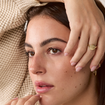 Solid gold signet ring styled on a model’s hand, paired with other rings for an elegant look.