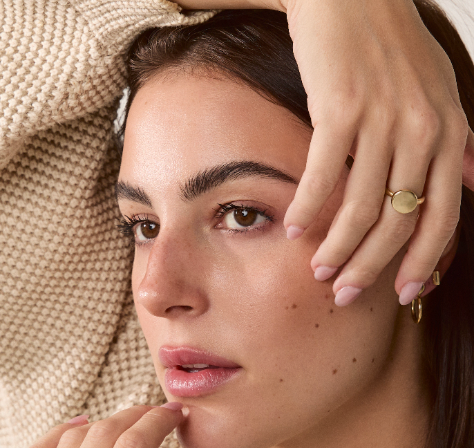 Solid gold signet ring styled on a model’s hand, paired with other rings for an elegant look.