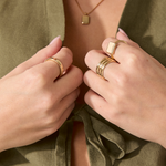 Hand wearing multiple solid gold rings, including the Everyday Band, showcasing stacked styling.