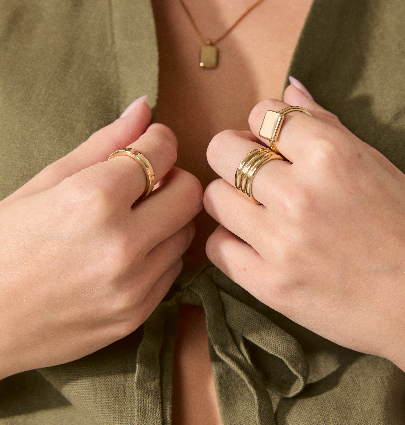 Hand wearing multiple solid gold rings, including the Everyday Band, showcasing stacked styling.