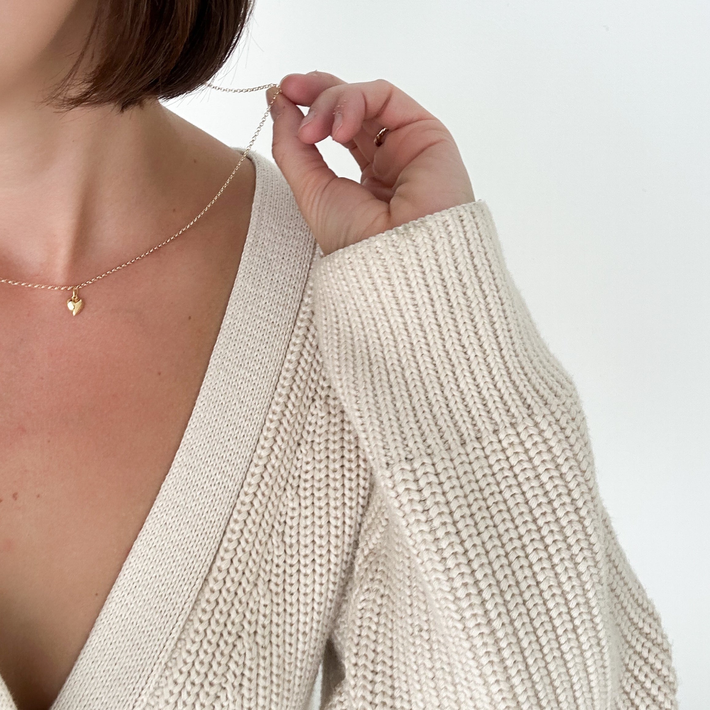 Model wearing the Lou Puff Heart Necklace in gold fill, styled with an elegant outfit to add warmth and sophistication.