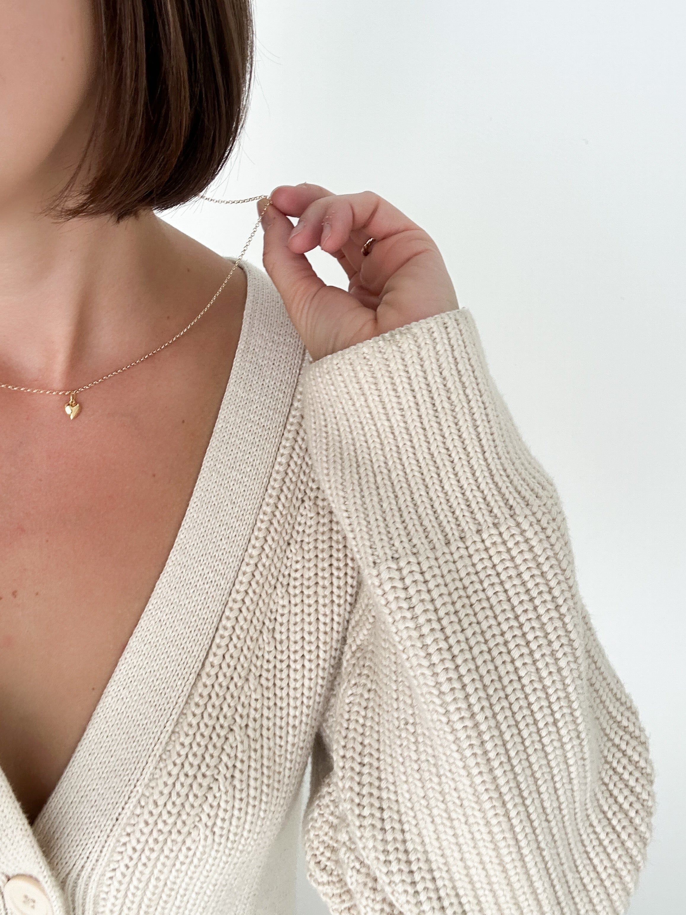 Model wearing the Lou Puff Heart Necklace in gold fill, styled with an elegant outfit to add warmth and sophistication.