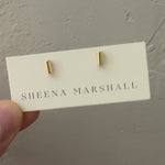 Solid gold tube stud earrings displayed on Sheena Marshall packaging