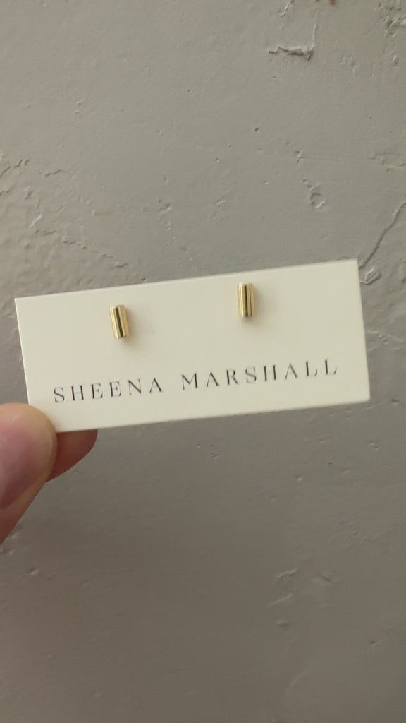 Solid gold tube stud earrings displayed on Sheena Marshall packaging