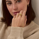 Woman wearing a beige sweater against a plain background