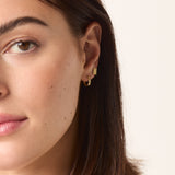 A person wearing a single gold ear stud.