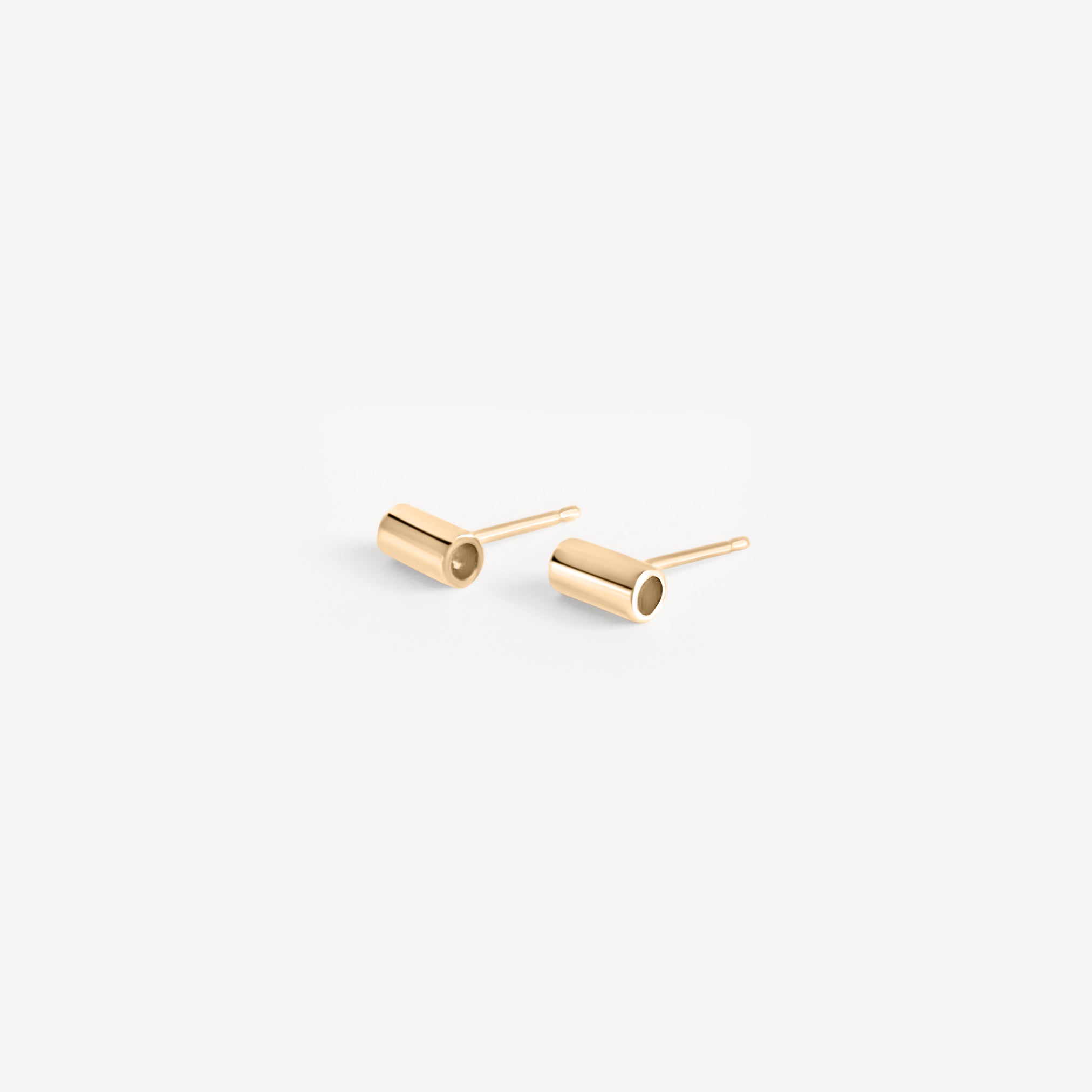 Solid gold tube stud earrings flatlay, highlighting minimalist design and craftsmanship.