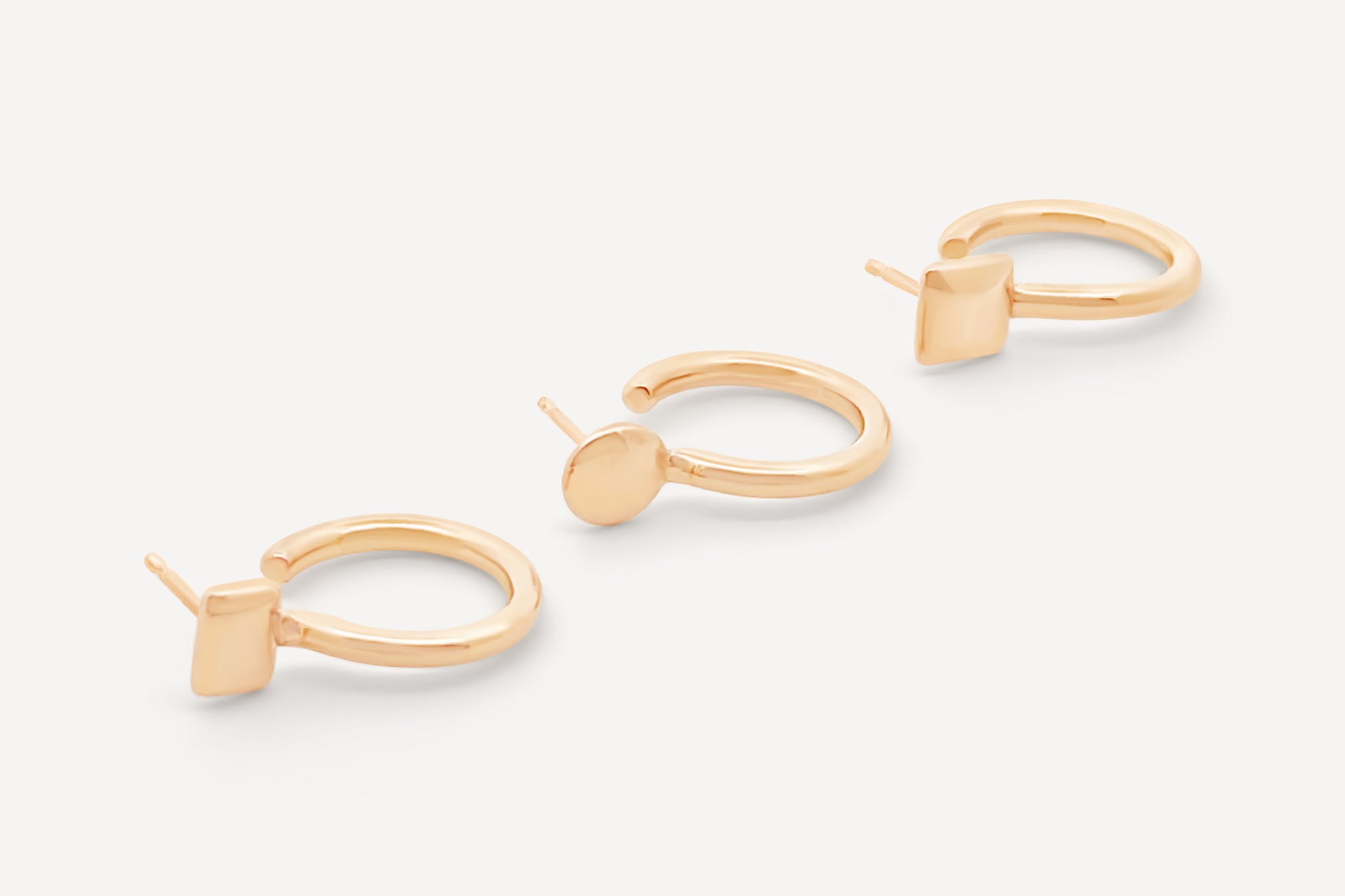 Trio of solid gold mini hoops featuring three distinct shapes: square, round, and oval, displayed on a neutral background.