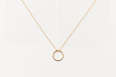 Flat lay of the Sol Circle Pendant Necklace in gold fill on a white background.
