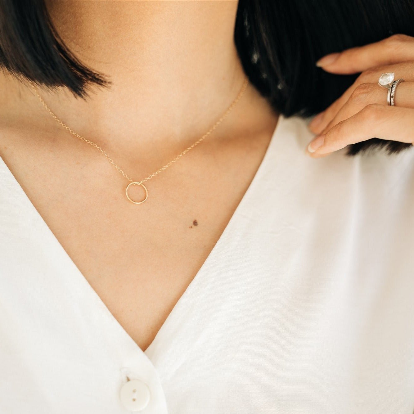 Woman wearing the Sol Circle Pendant Necklace in gold fill with a white blouse.