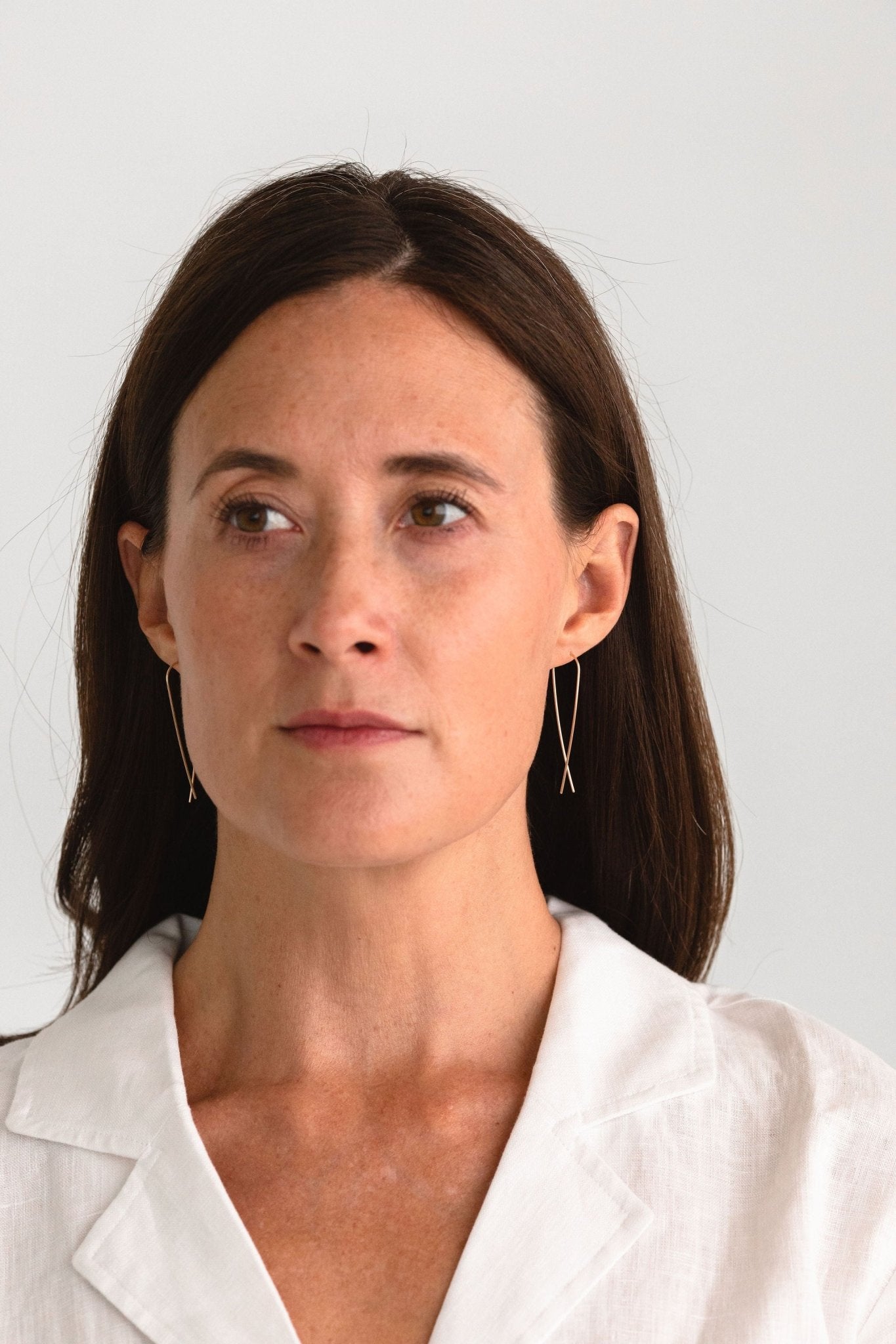 Woman wearing gold fill long threader earrings, showcasing the elegant and minimalist profile.