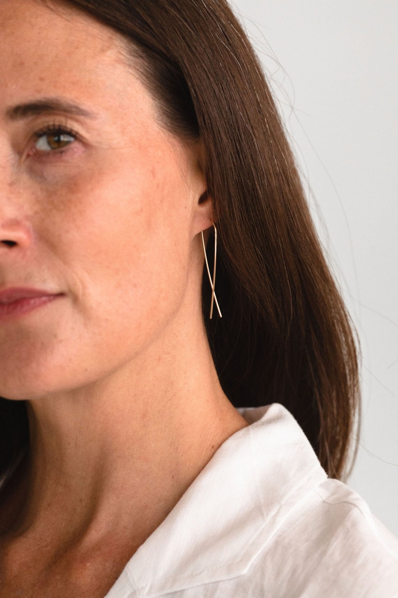 Woman wearing gold fill long threader earrings, showcasing the elegant and minimalist profile.