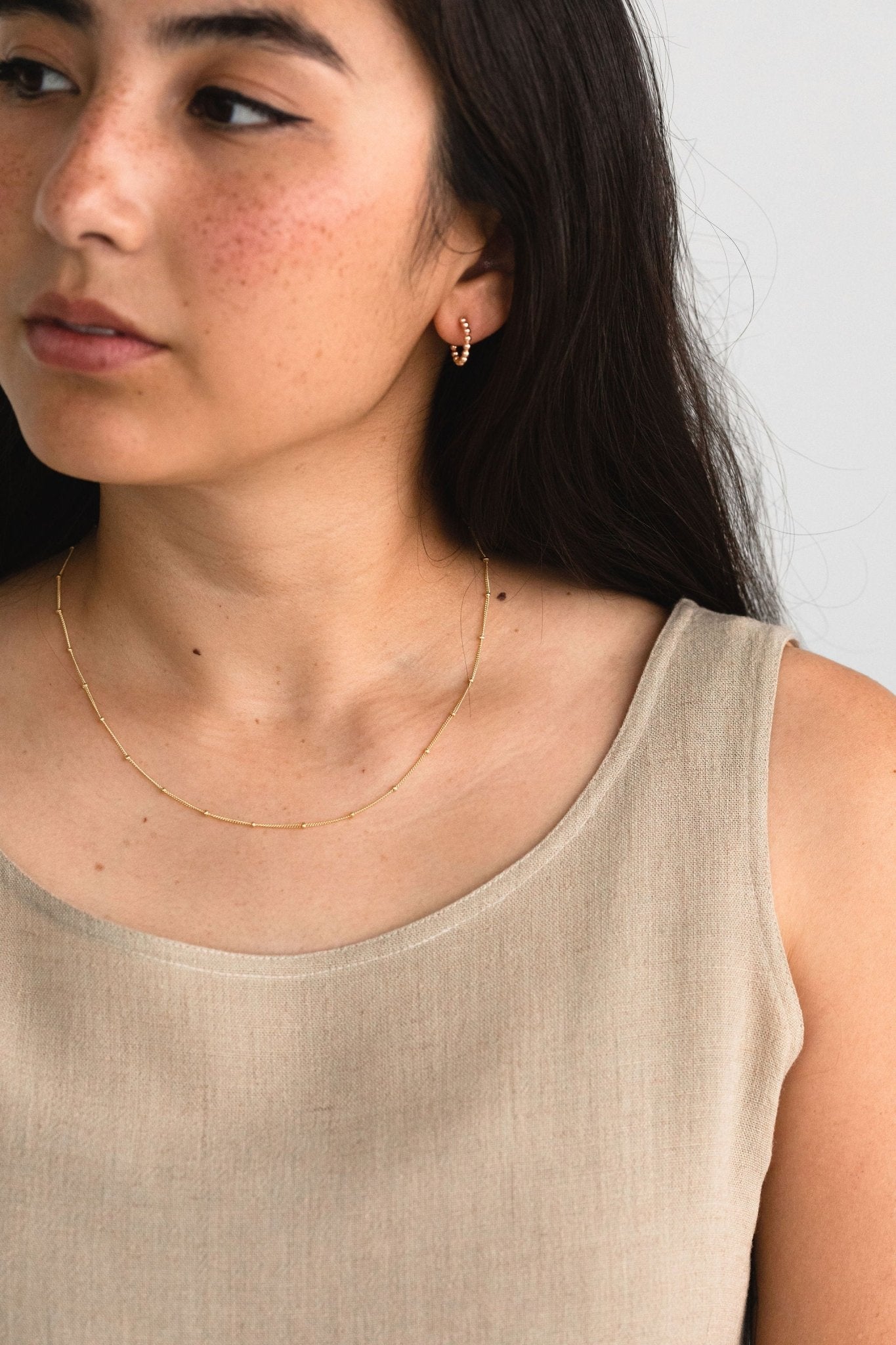 Gold fill satellite chain necklace worn by a model with neutral styling.