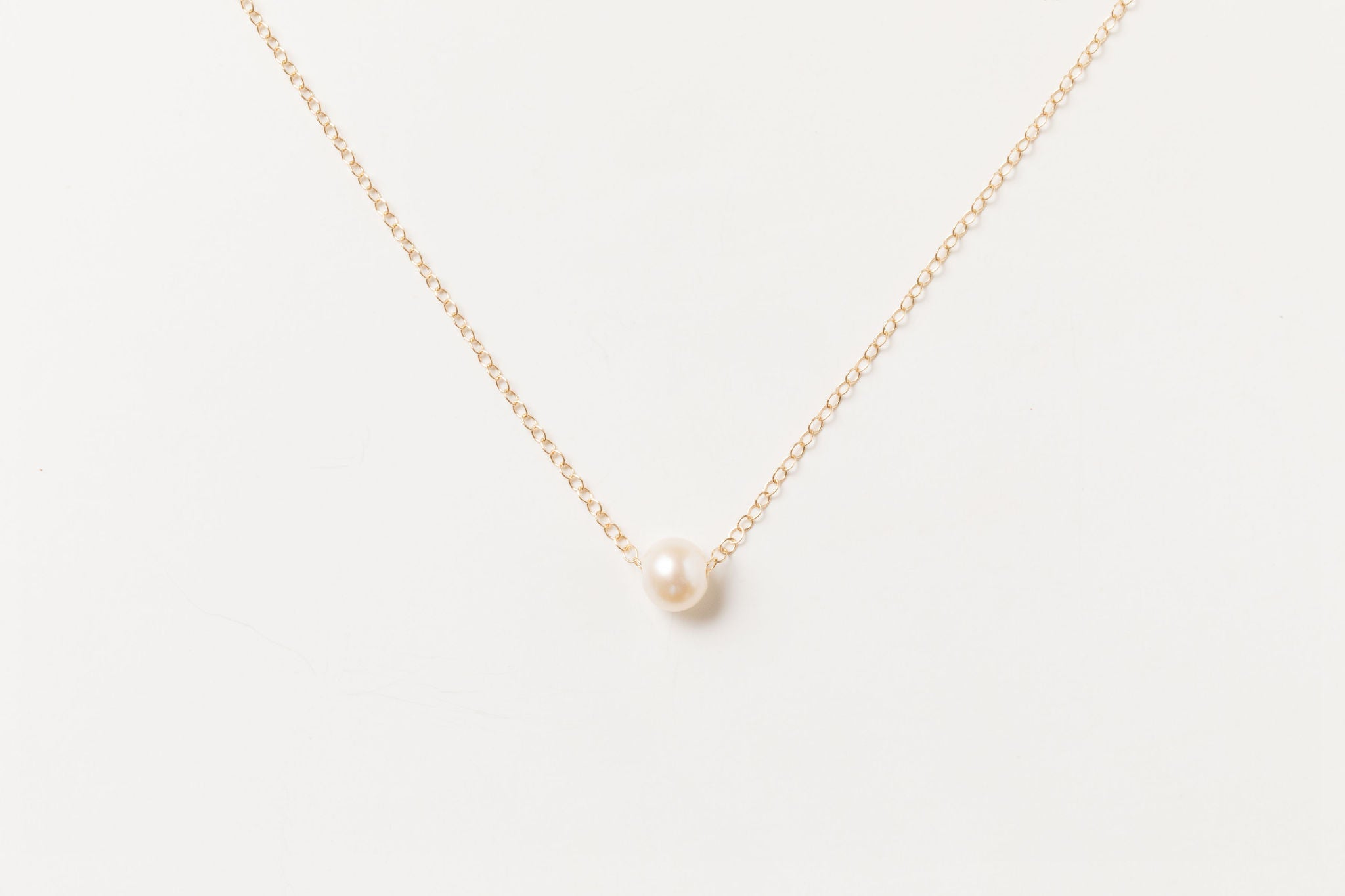 Grit Necklace in 14k gold fill with a single freshwater pearl, displayed on a white background.
