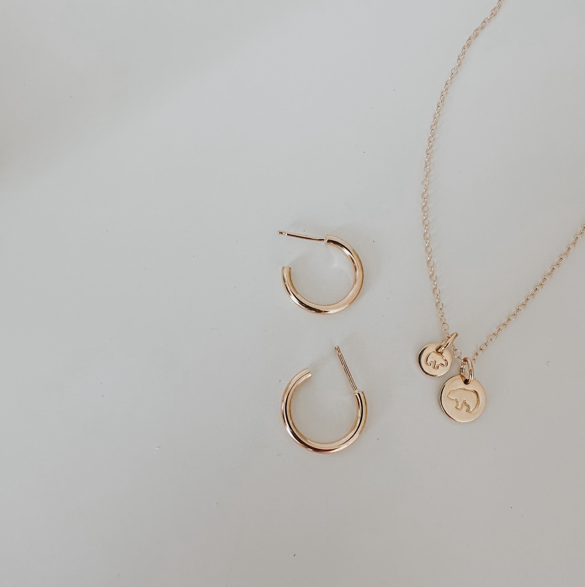 Mama Bear Baby Bear necklace layered with delicate gold fill hoop earrings jewelry for a casual and elevated everyday outfit. 