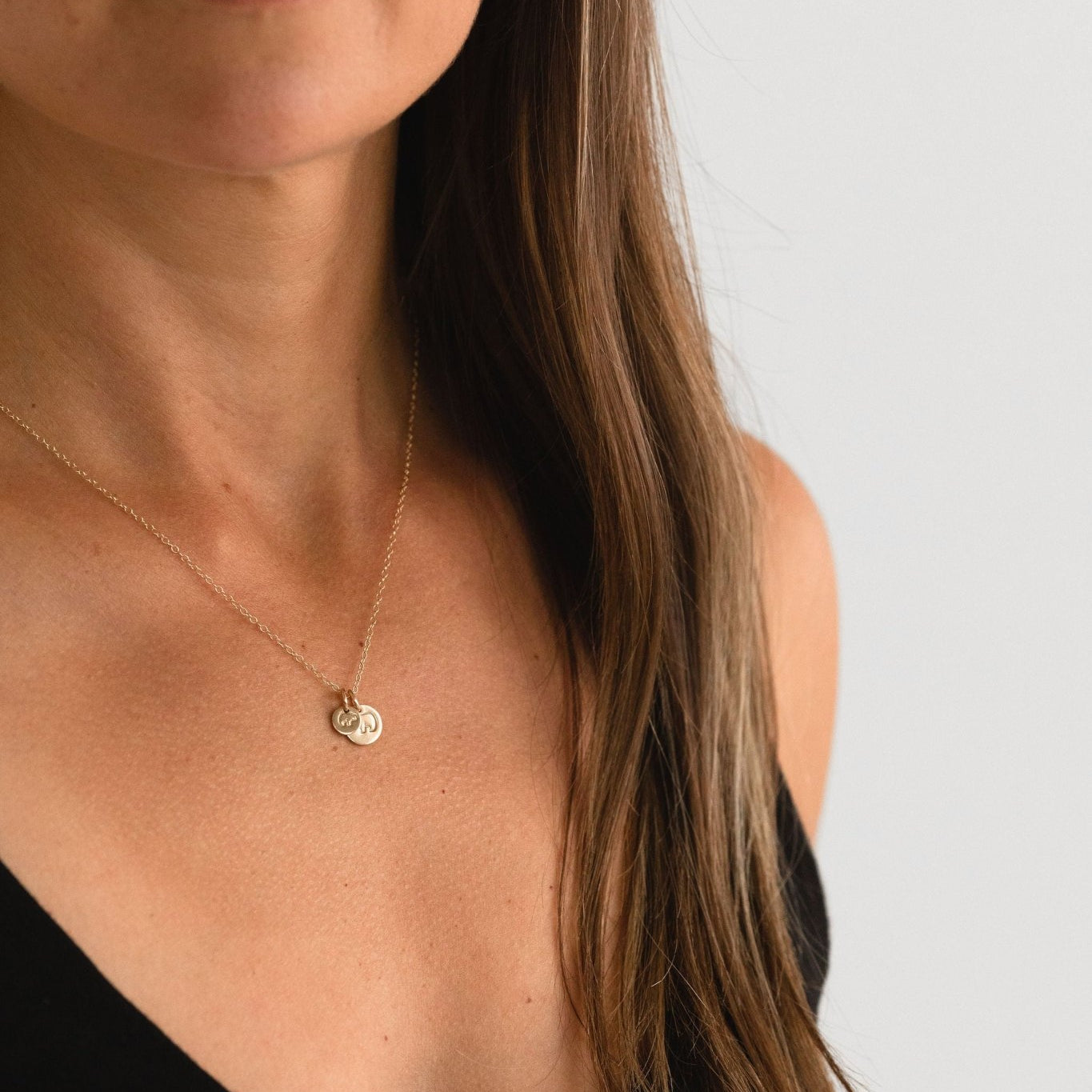 Model wearing Mama Bear Baby Bear necklace, hand-stamped with a gold fill heart-shaped pendant.