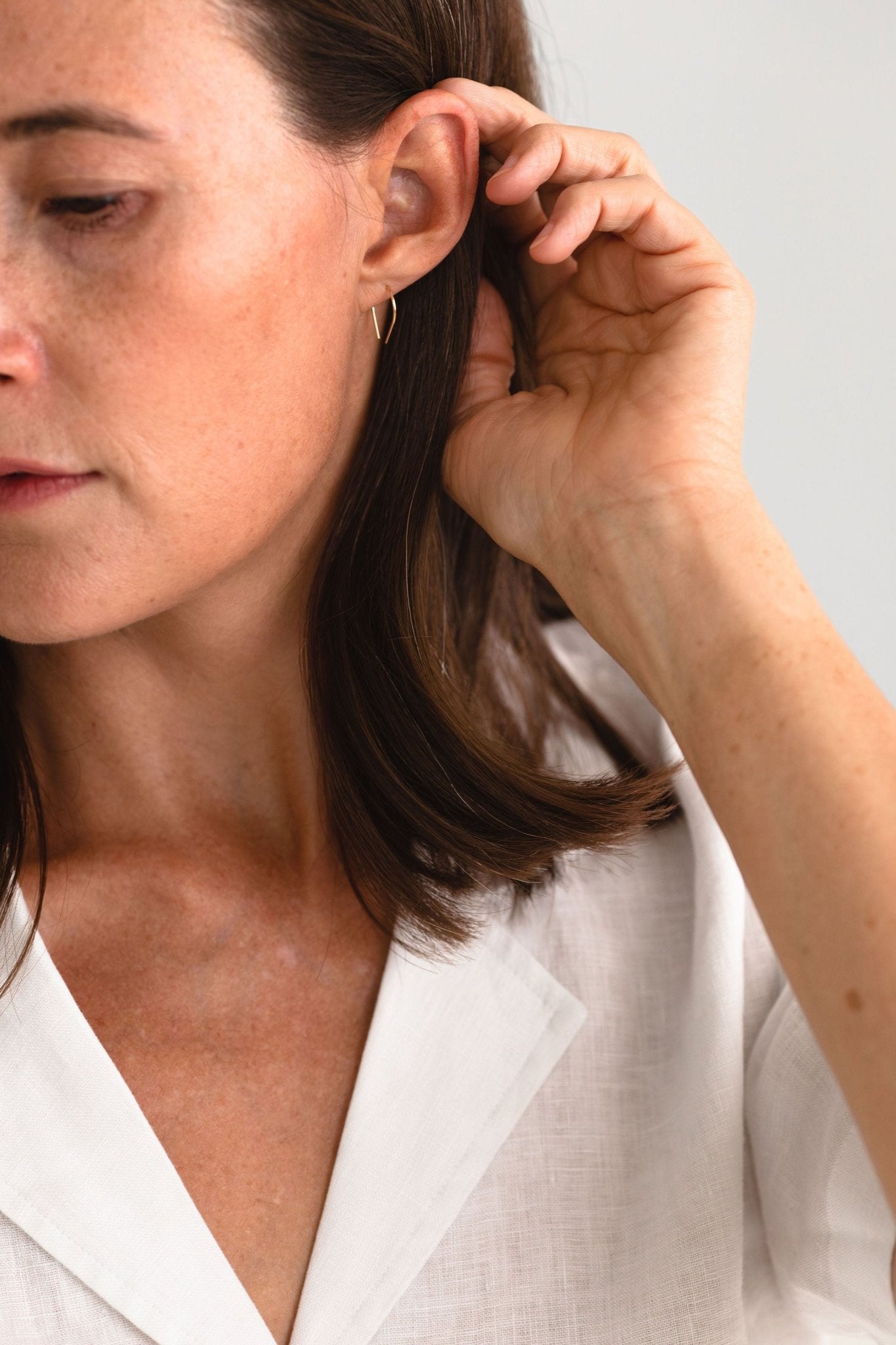 Woman wearing the Moab Arch Threader Earrings, showcasing their lightweight design and stylish fit.