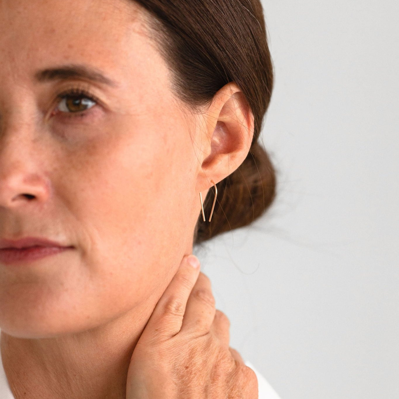 Woman wearing Palmer Arch Threader Earrings, showcasing their delicate gold-filled arc and lightweight design in a side profile.