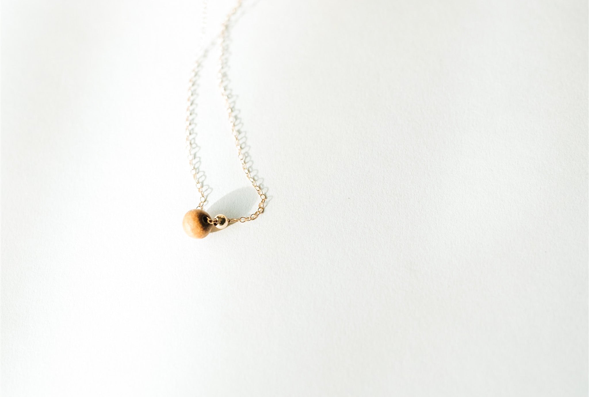 Minimalist Sandalwood Bead Necklace by Sheena Marshall Jewelry, featuring an ethically sourced sandalwood bead and gold-filled chain for refined elegance.